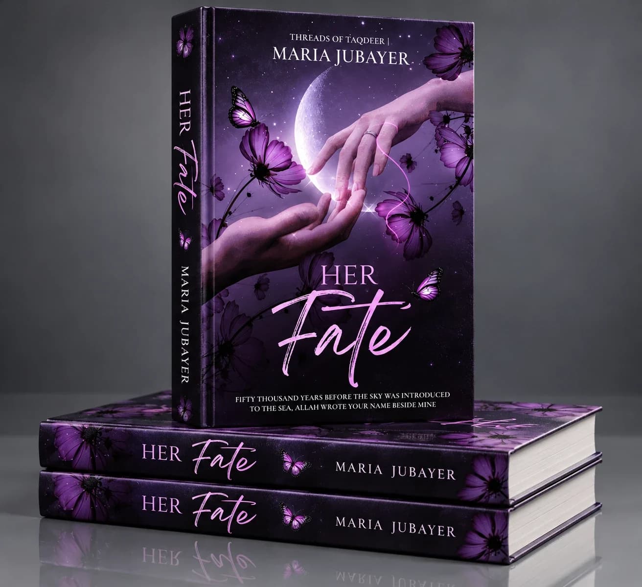 Hardcover mockup of Her Fate by Maria Jubayer, Threads of Taqdeer: one book standing on two stacked copies, its purple cover showing two hands joined by a glowing pink thread beneath a crescent moon, with purple flowers, butterflies and the title in serif and script lettering.